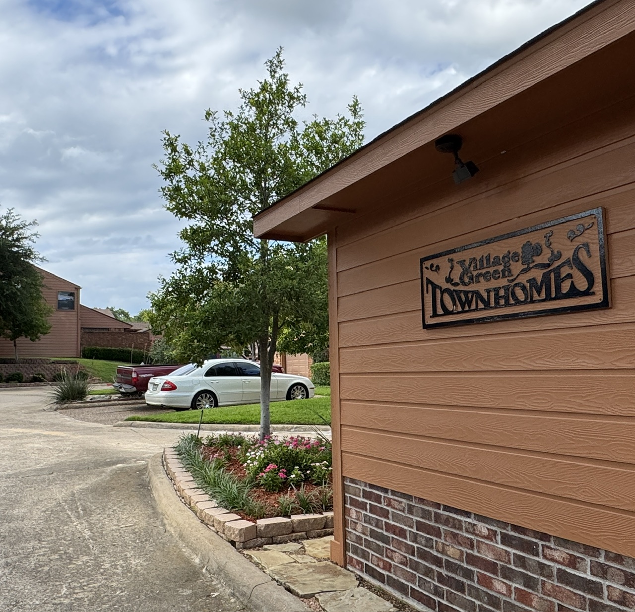 Village Green Townhomes entrance sign in Denison, Texas — the original 1982 development by James Green, founder of Village Green Custom Homes